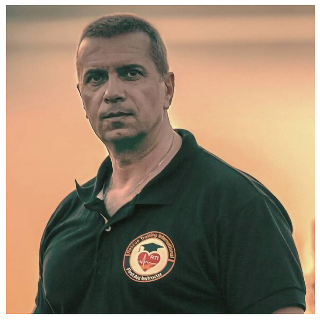 Grigoris Lampros, a professional Motorcycle Safe Riding and First Aid Instructor, standing beside a motorcycle in his training center.